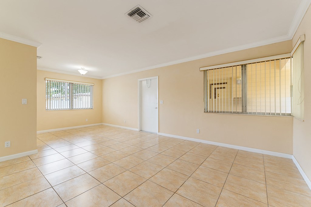 an empty living room with tiled floors and a window