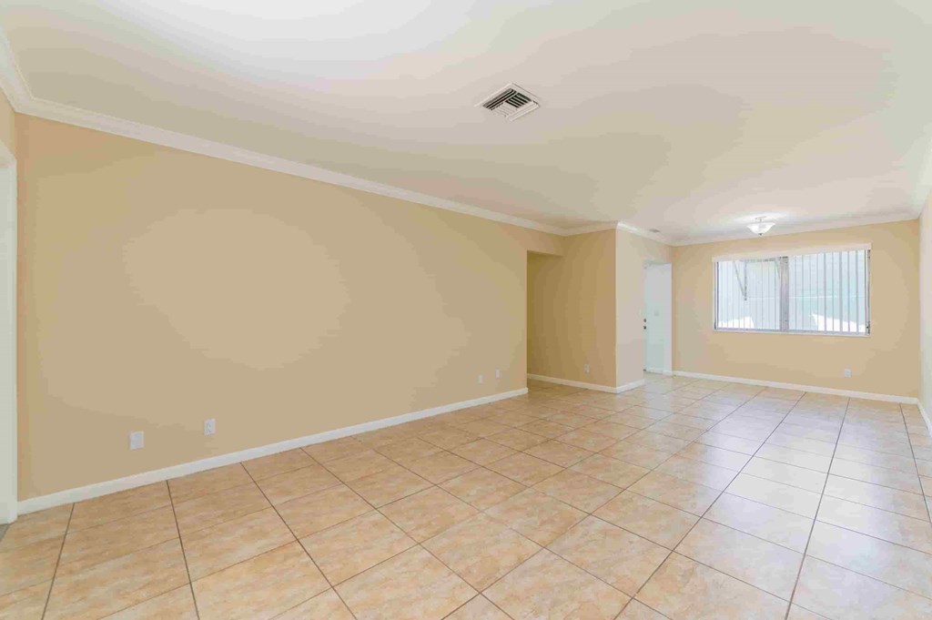 an empty living room with beige walls and a tiled floor
