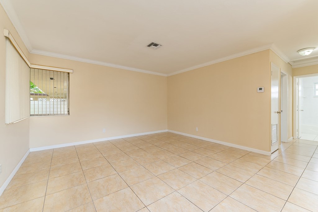 an empty living room with beige walls and a tiled floor