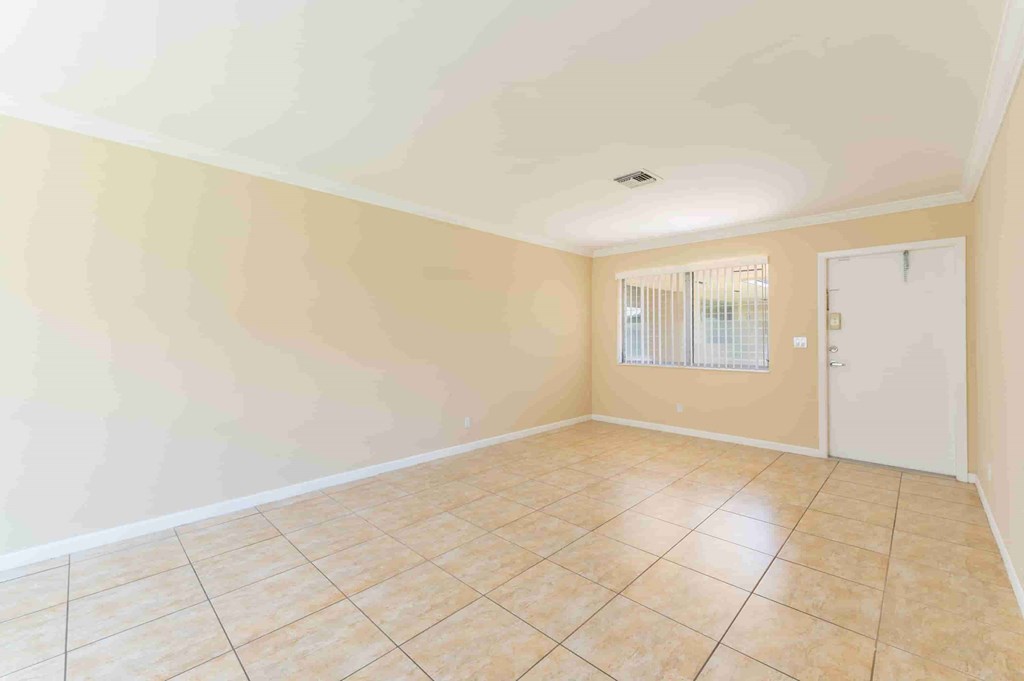 an empty living room with tiled floors and a door