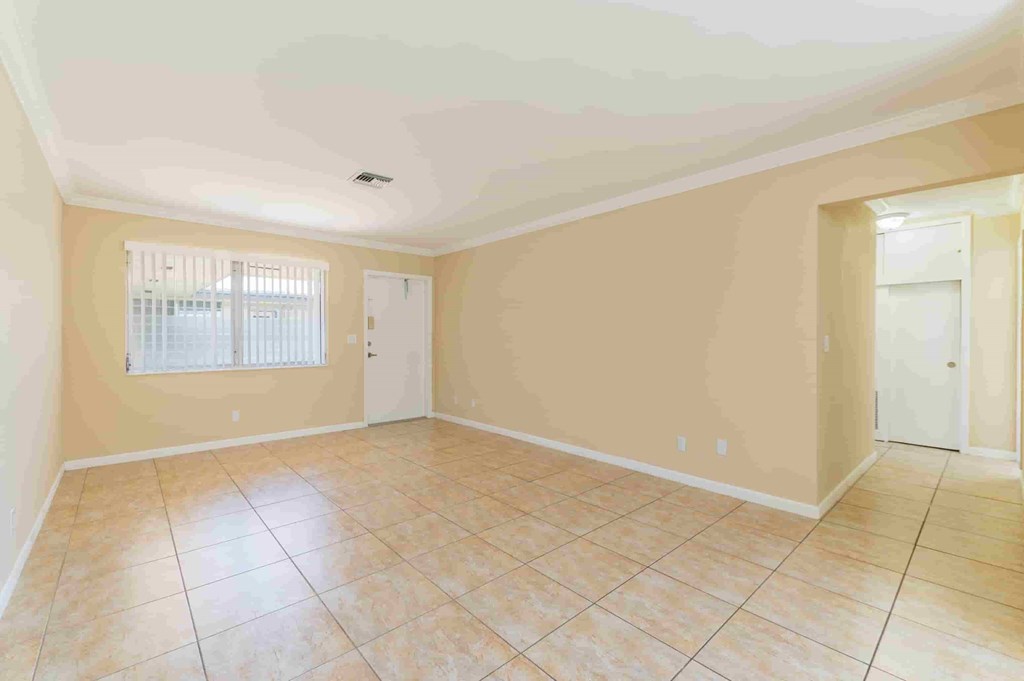 an empty living room with beige walls and a tiled floor