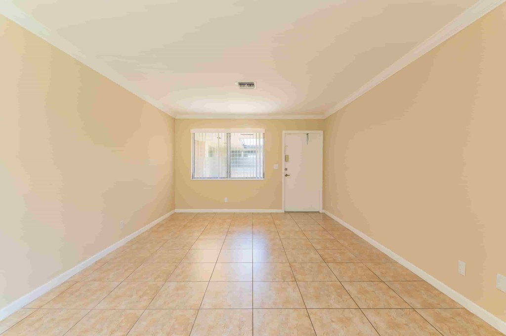 an empty living room with tiled floors and a door