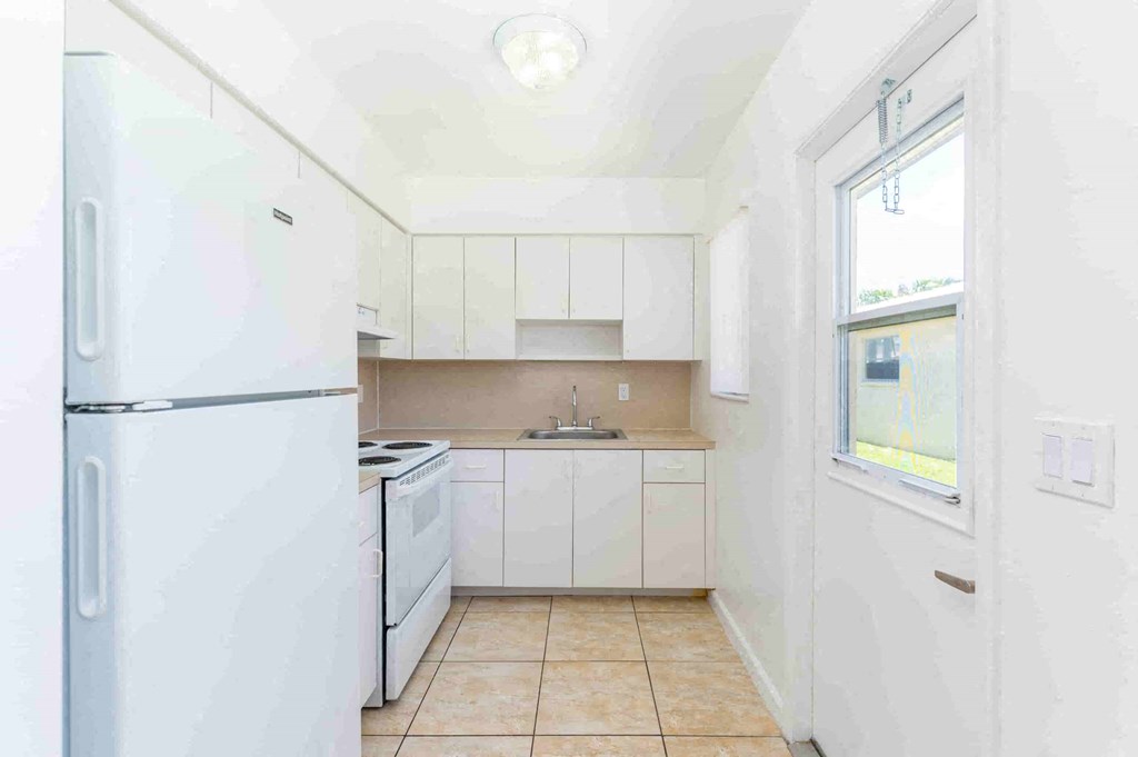 a kitchen with white cabinets and a white refrigerator