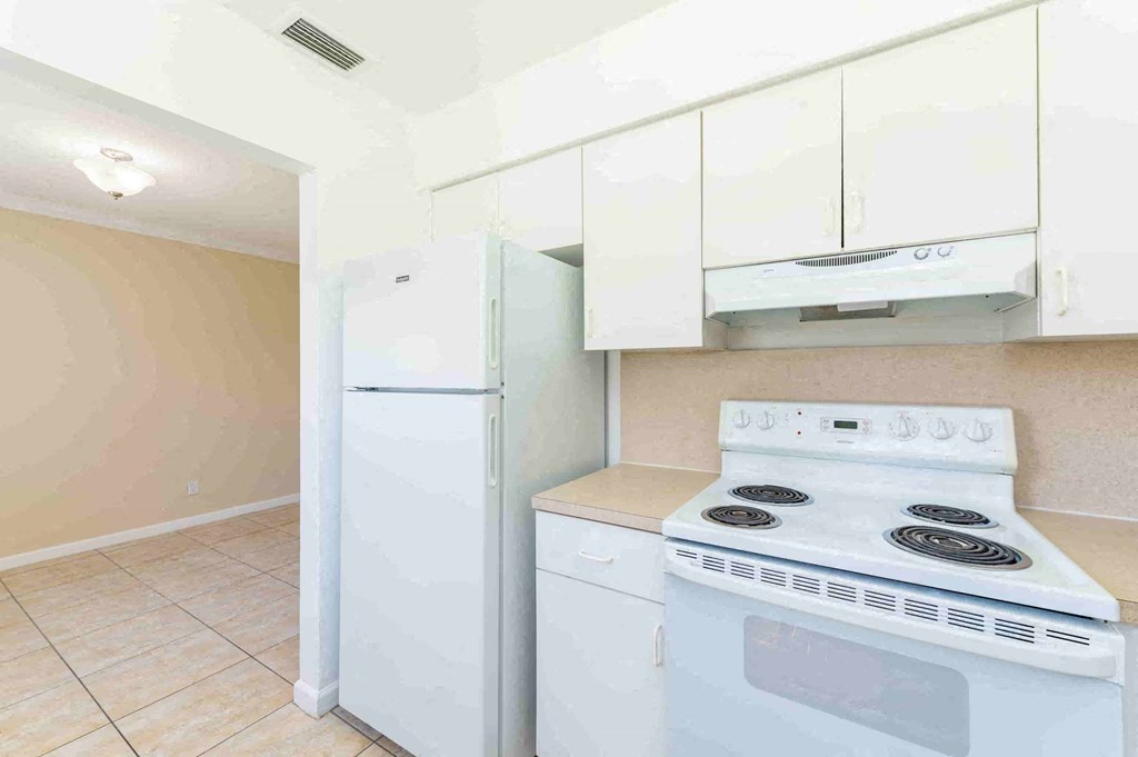 a kitchen with white appliances and white cabinets and a refrigerator