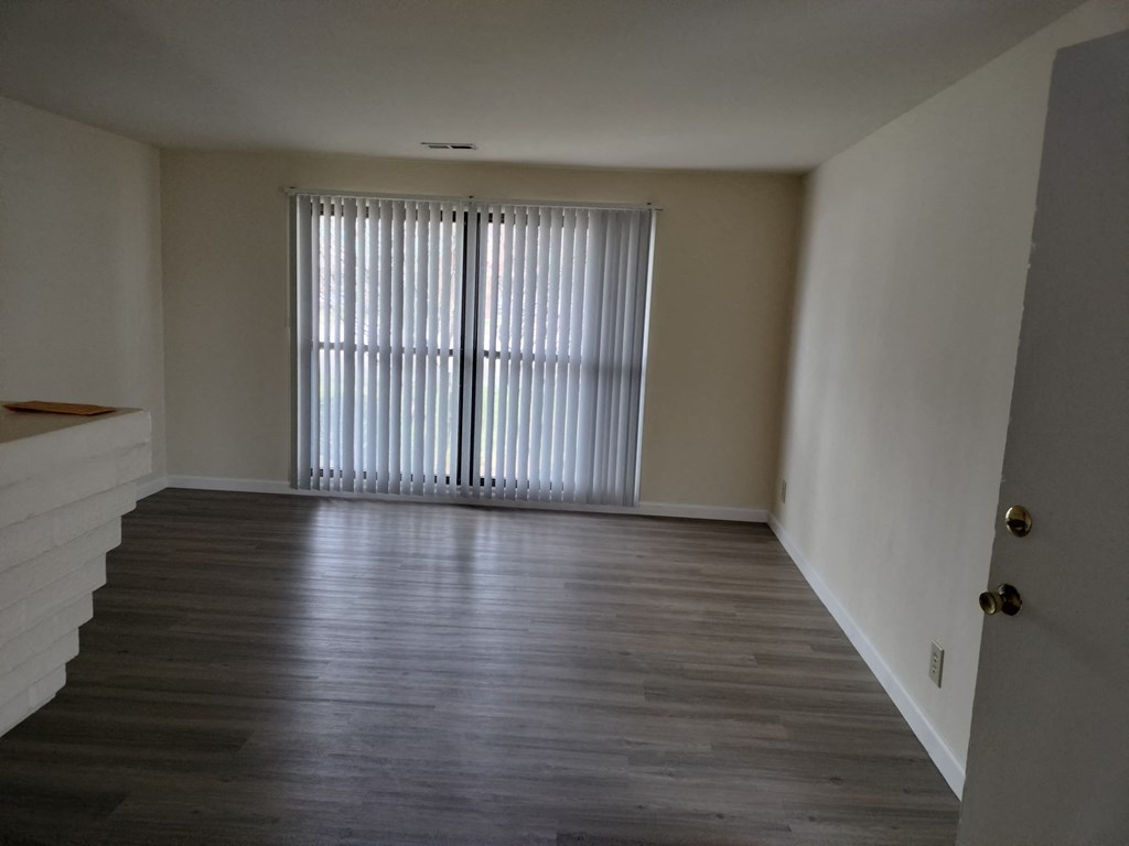 an empty living room with wood floors and a large window