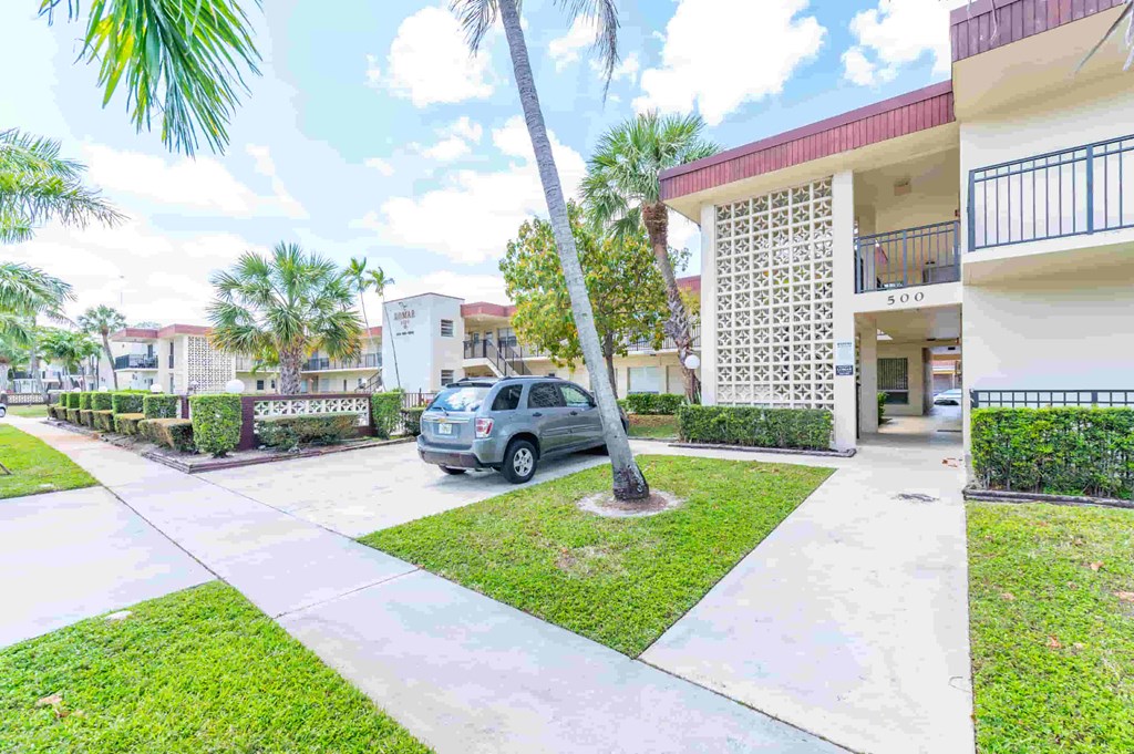 a car parked in front of a villa with a palm tree