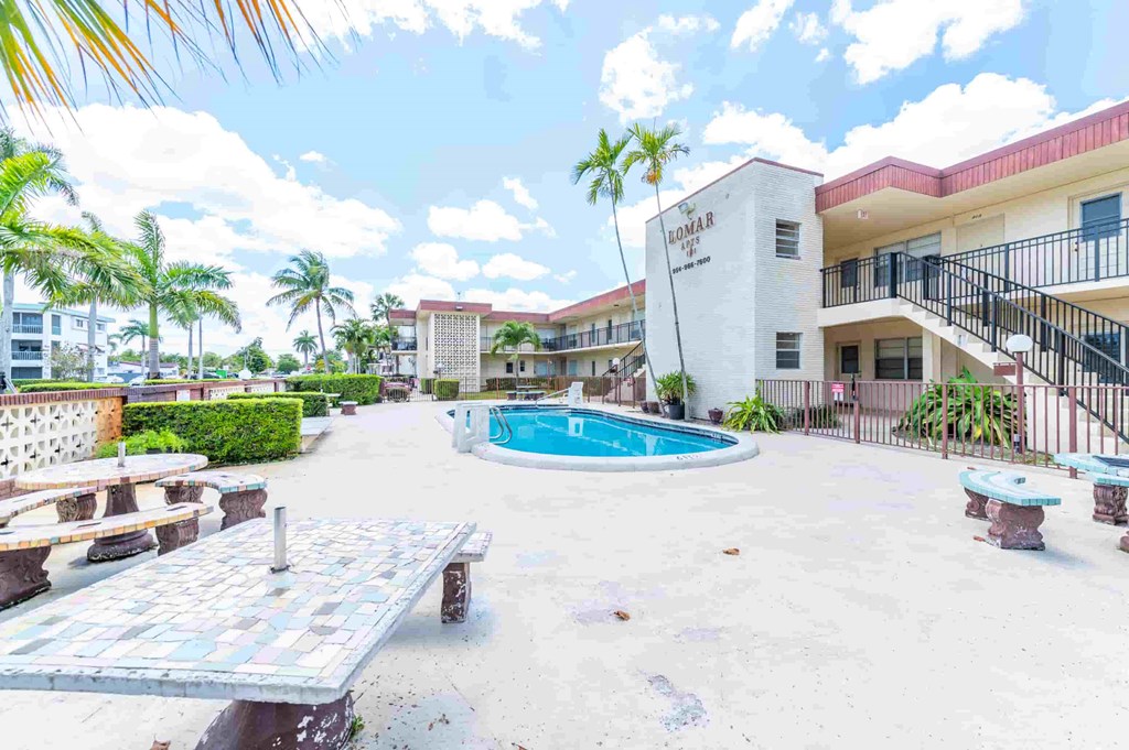a building with a swimming pool and picnic tables in front of it