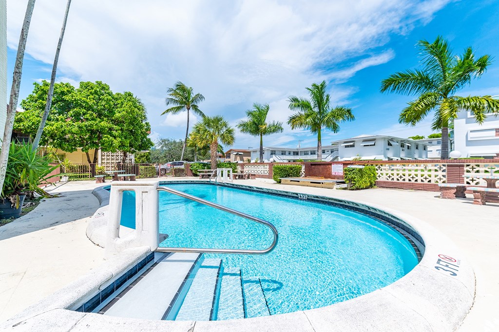 a swimming pool with palm trees and a house in the background