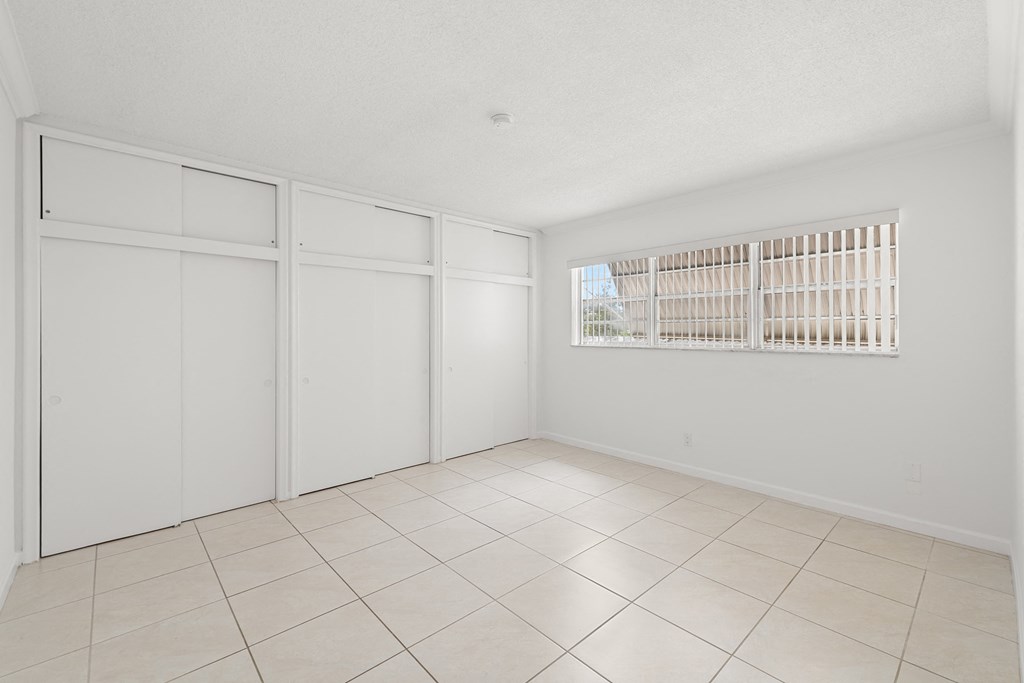 a spacious living room with tiled floors and white walls