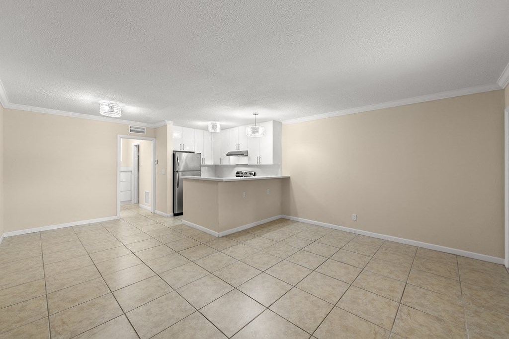 the living room and kitchen of a house with a tiled floor