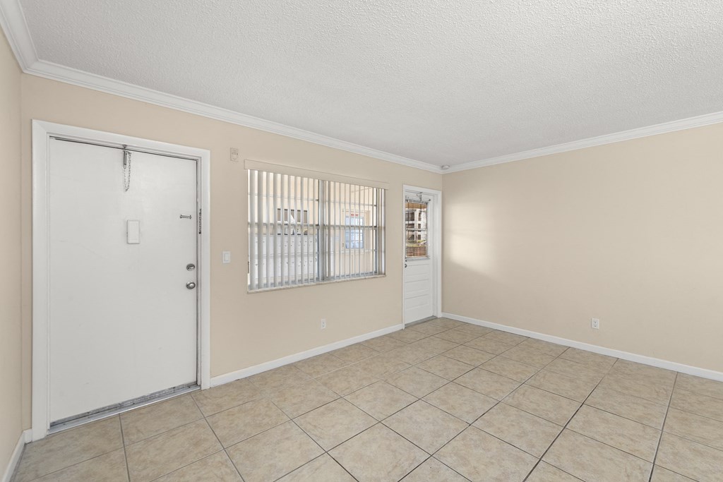 an empty living room with a door and a tiled floor