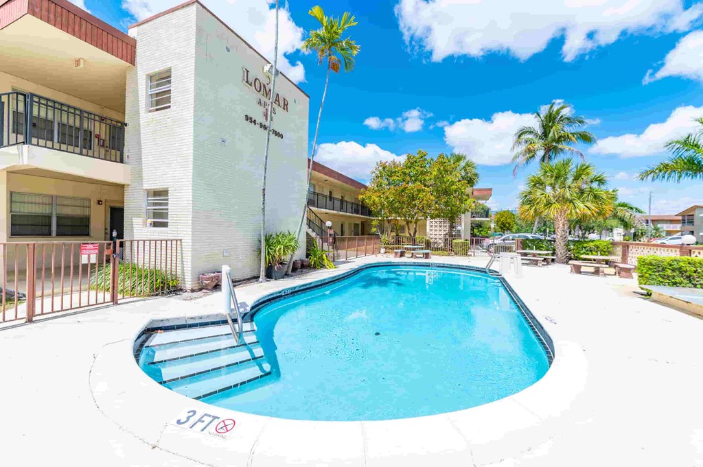 a swimming pool in front of a building with a resort style pool