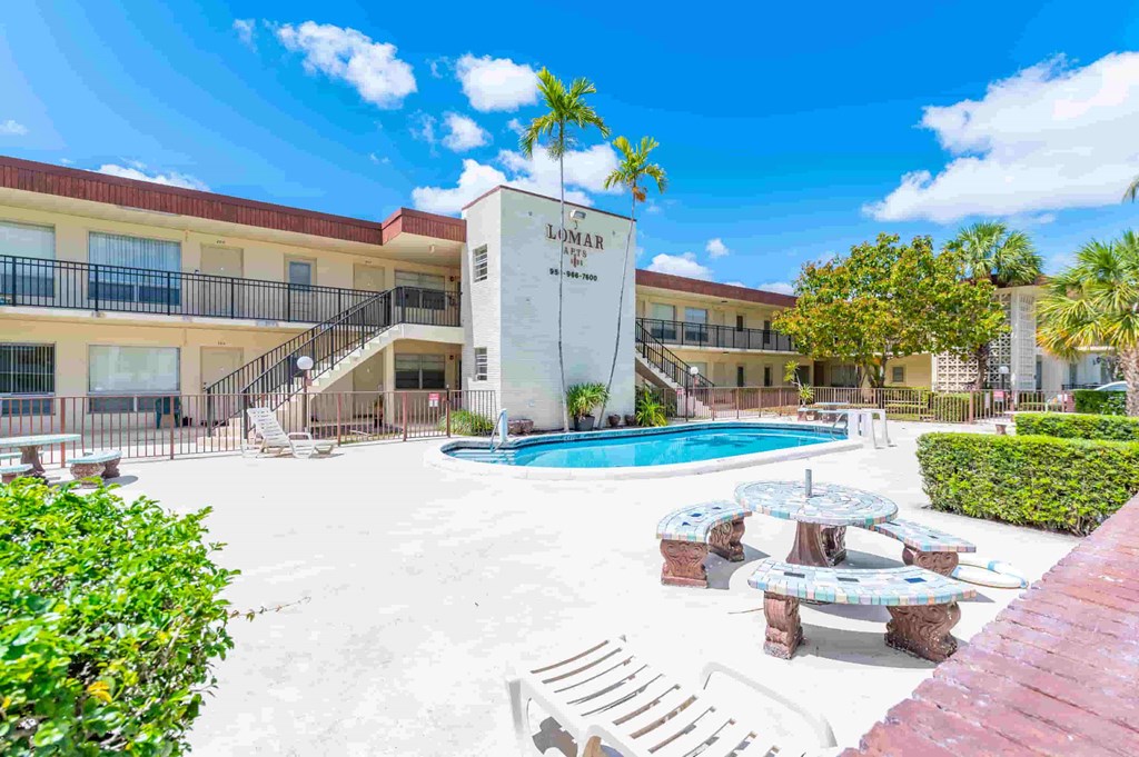 a building with a swimming pool and tables in front of it