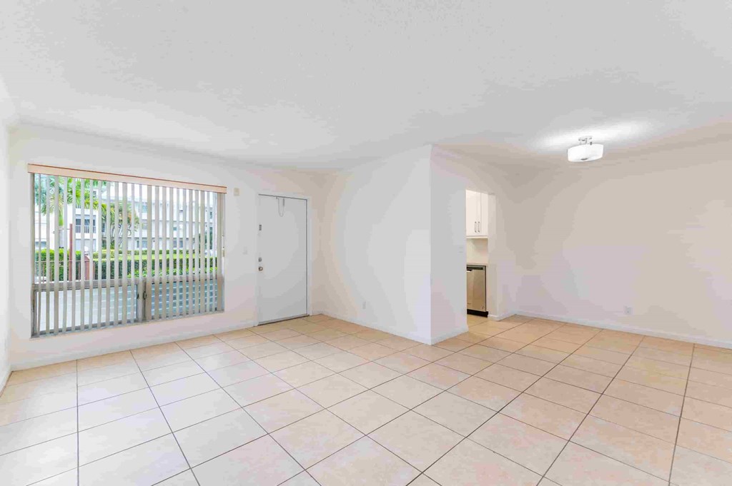 an empty living room with a large window and tiled floors
