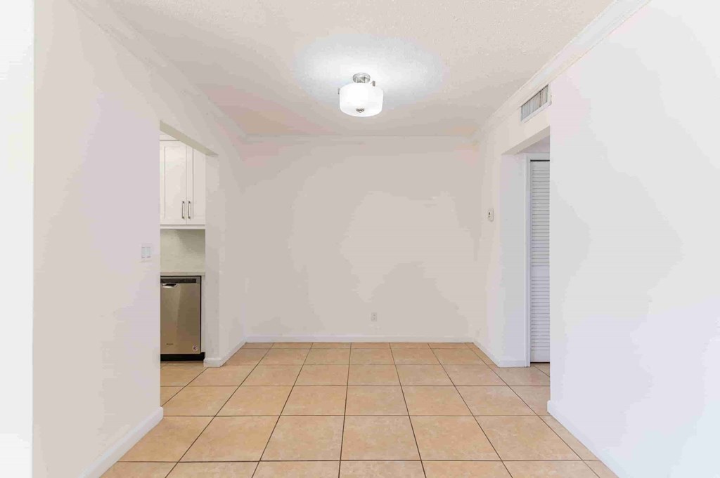 an empty living room with white walls and a tiled floor