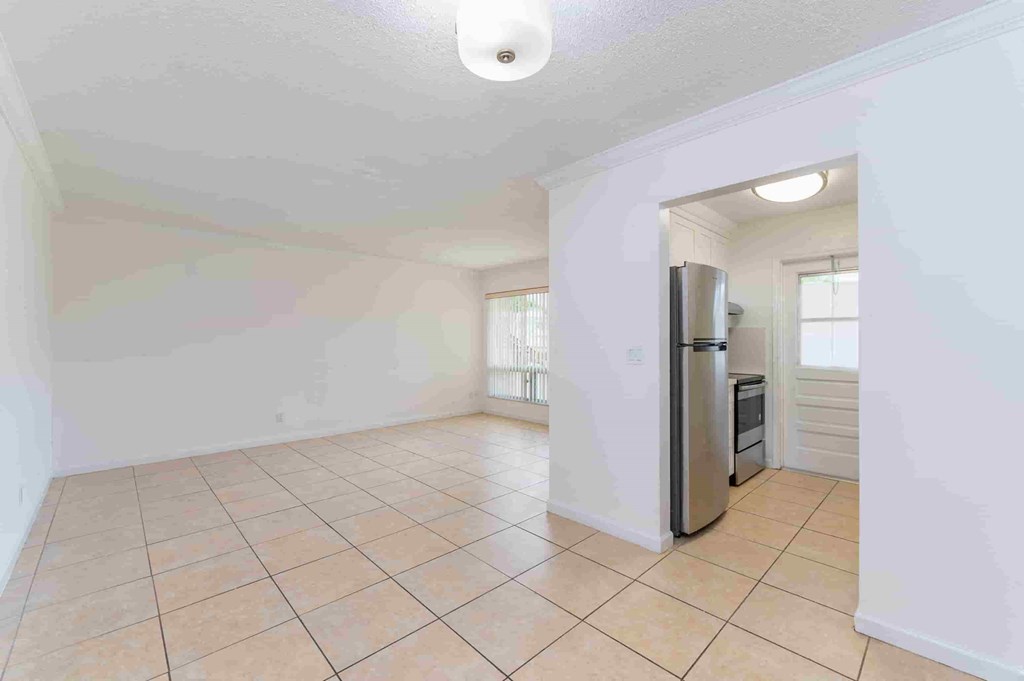an empty kitchen and living room with a refrigerator