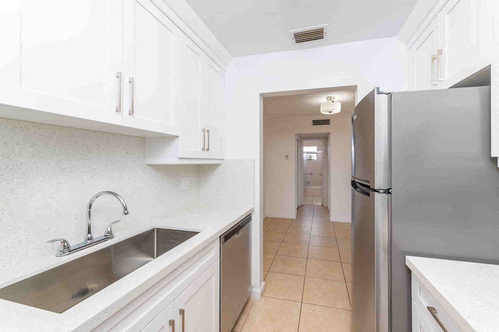 a kitchen with white cabinets and a sink and a refrigerator