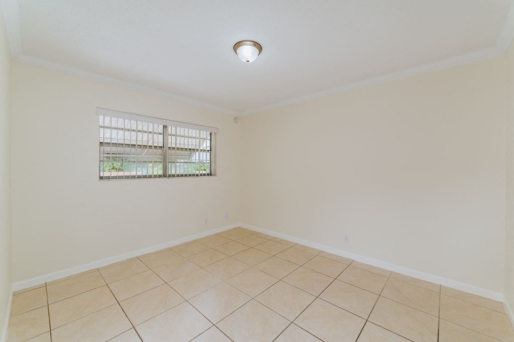 an empty living room with tiled floors and a window