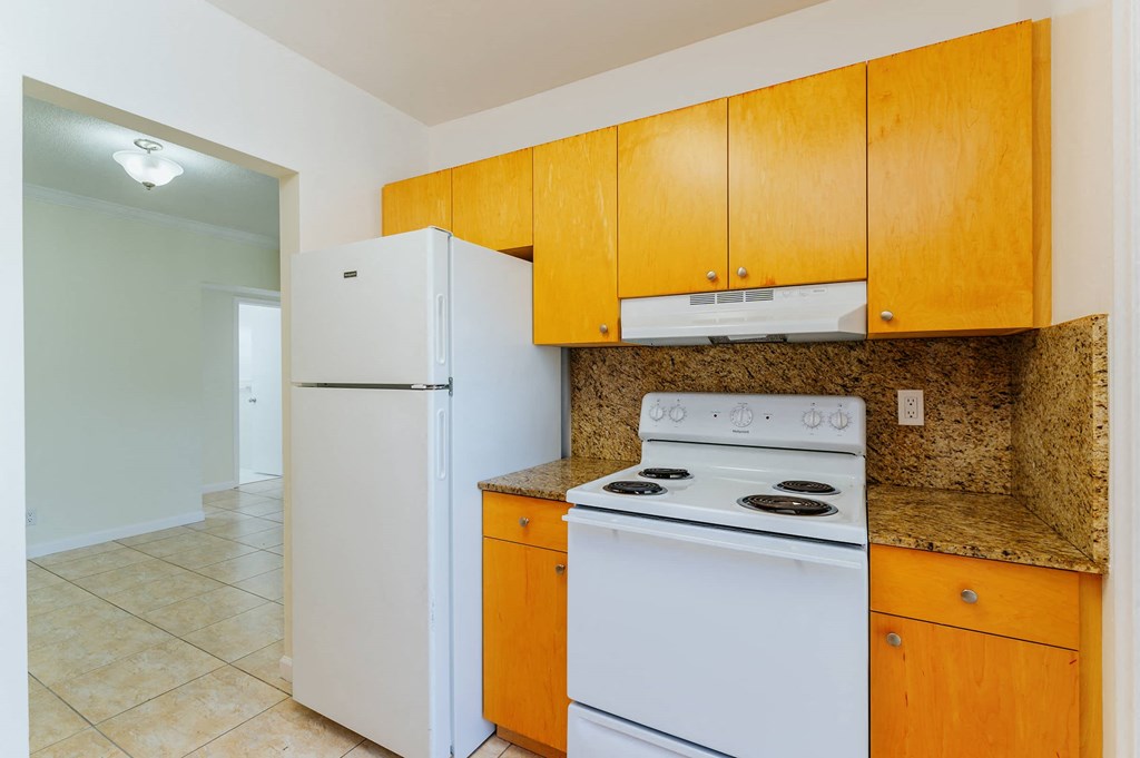 a kitchen with white appliances and wooden cabinets and a refrigerator