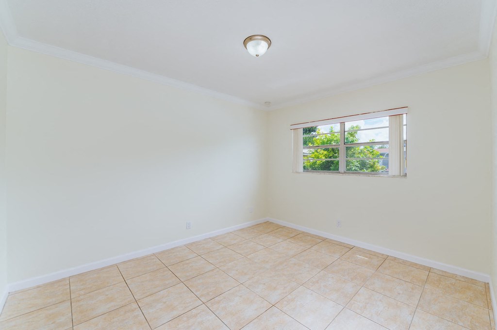 an empty living room with a window and a tiled floor
