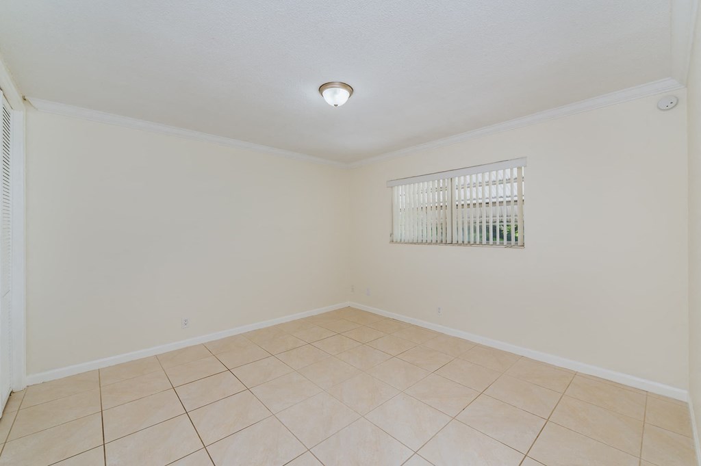 an empty living room with tiled floors and a window