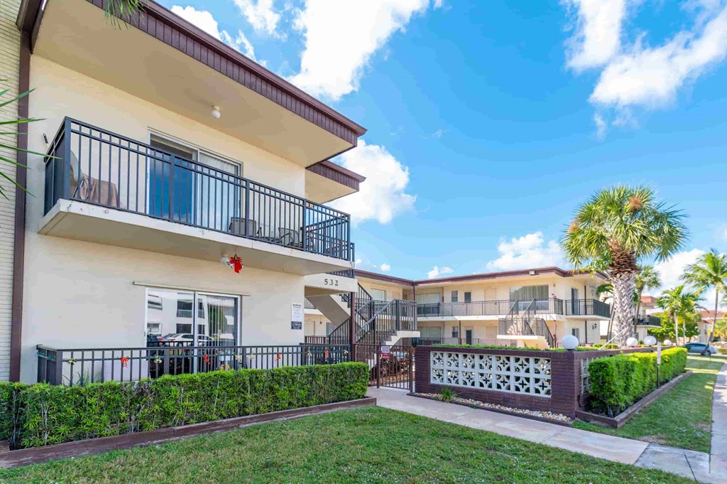 a building with a yard and a balcony in front of it