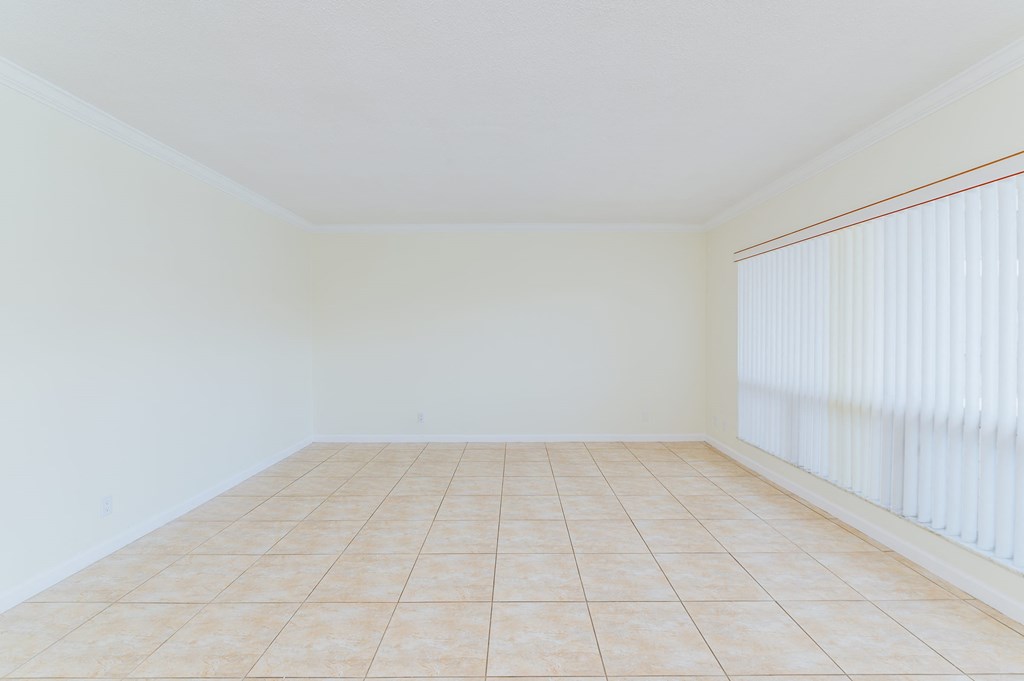 an empty living room with a large window with white blinds