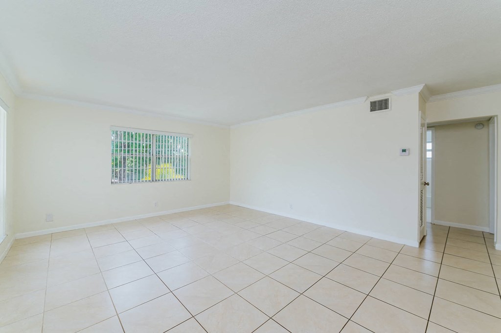 a spacious living room with tiled flooring and a door
