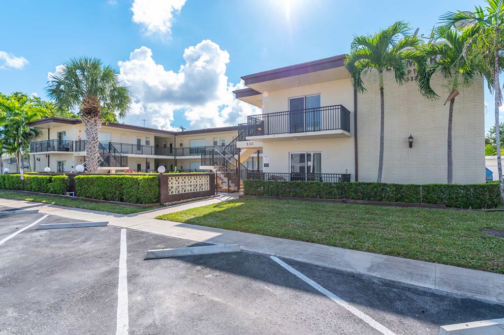 a building with palm trees in front of a parking lot