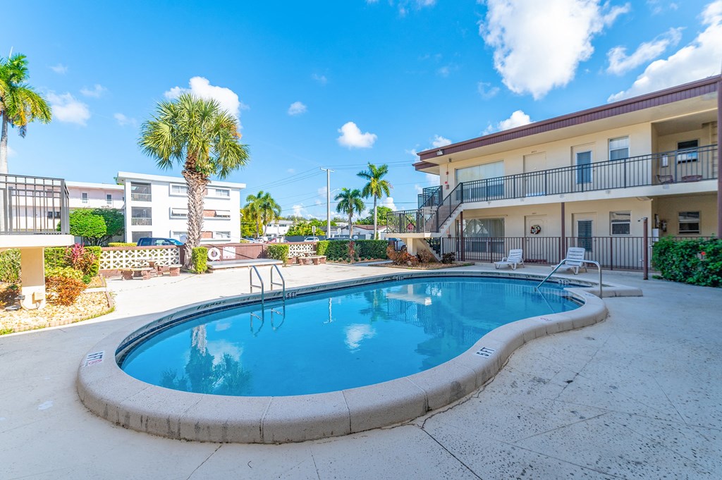 a swimming pool with a building in the background and palm trees