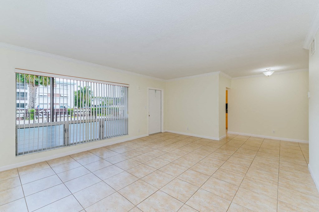a spacious living room with a large window and a tiled floor