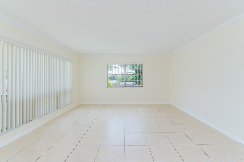 an empty living room with white tiles and a window