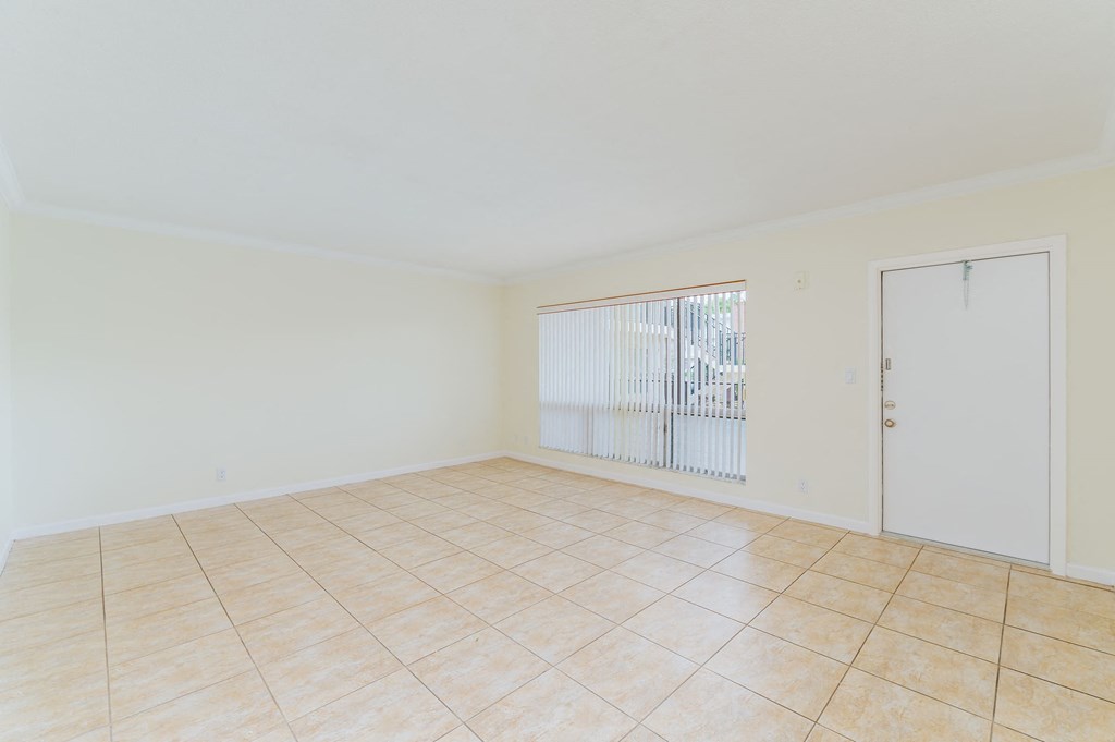 an empty living room with a sliding glass door and a tiled floor
