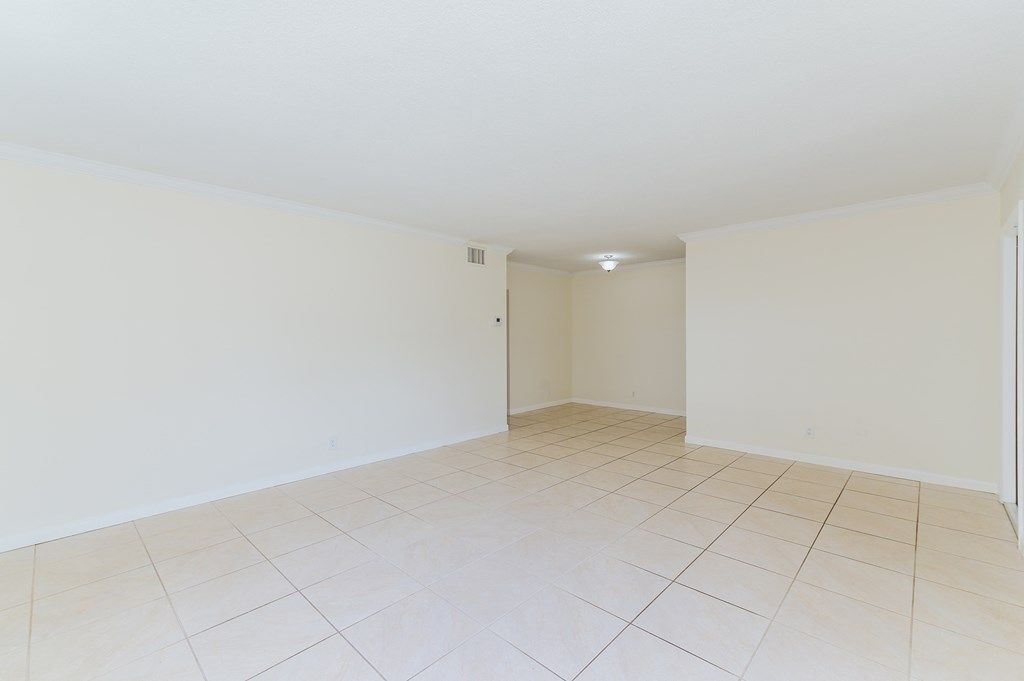 an empty living room with a tiled floor and white walls