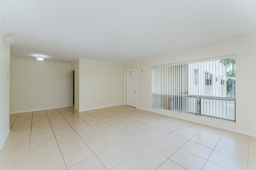 an empty living room with a large window and tiled floors