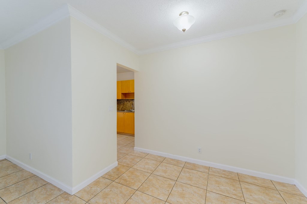 a empty living room with a tile floor and white walls