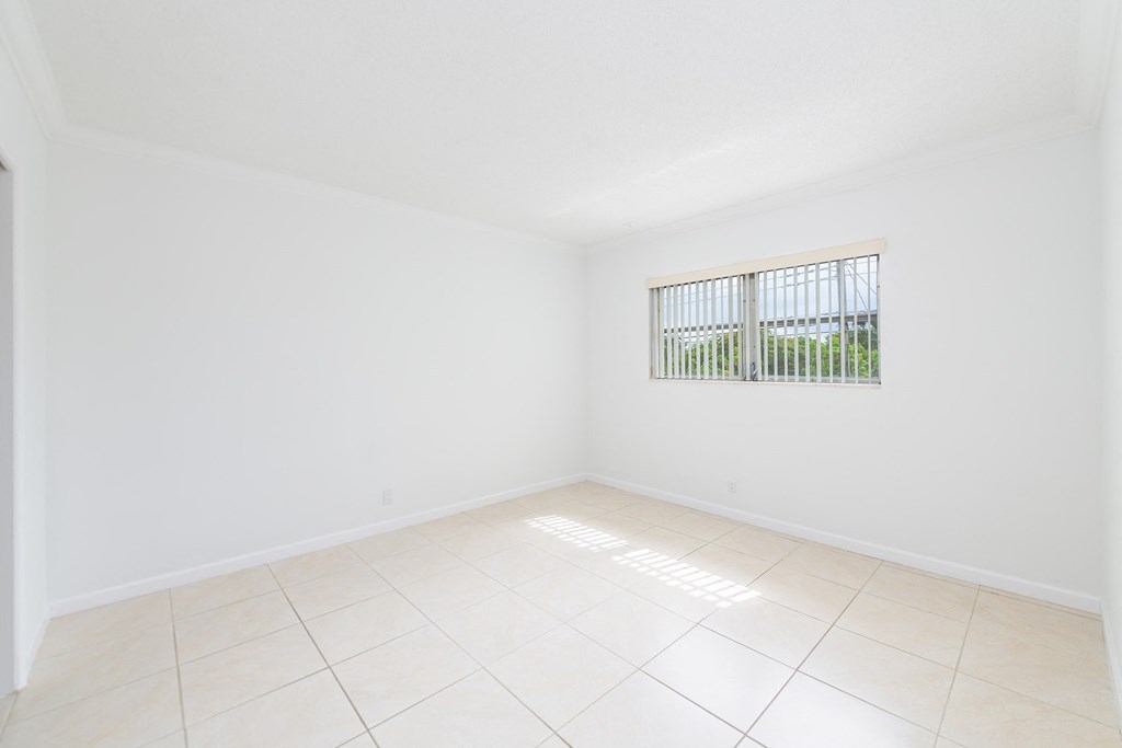 an empty living room with a window and a tiled floor