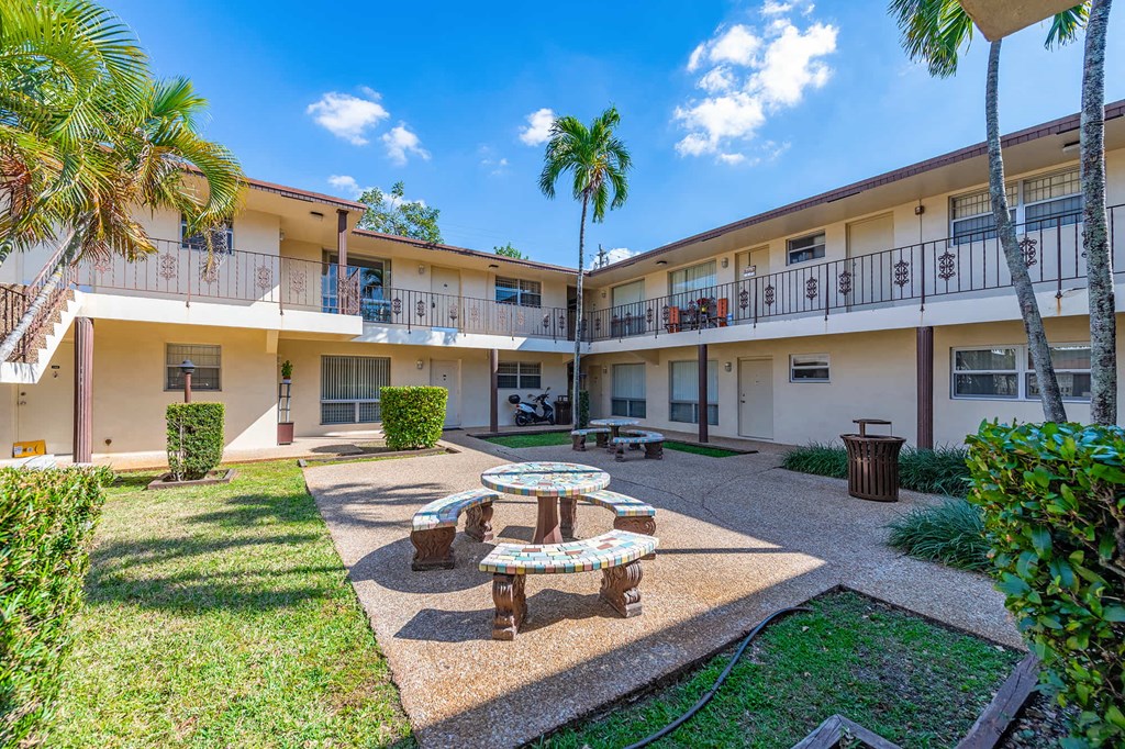 a courtyard with a table and benches in front of a building