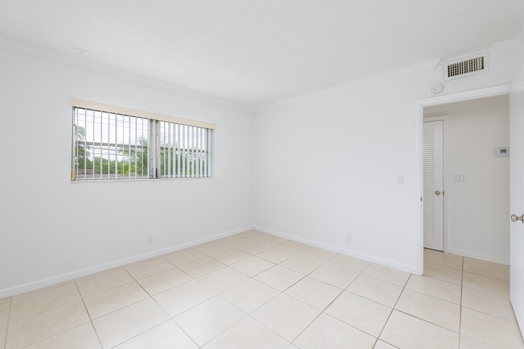 an empty living room with a window and a tiled floor