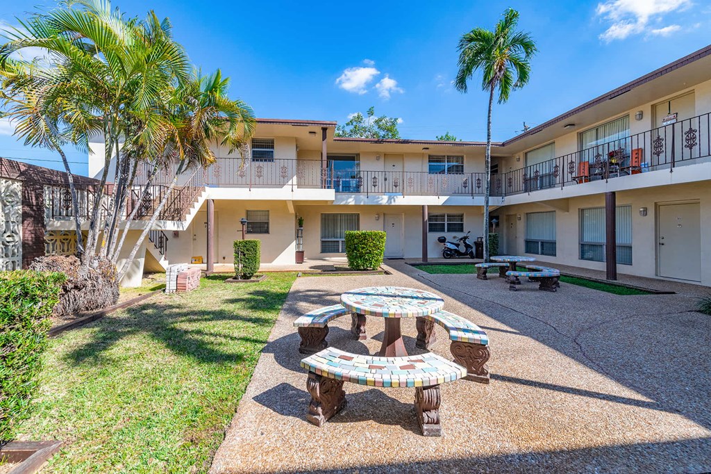 a courtyard with a table and benches in front of a building
