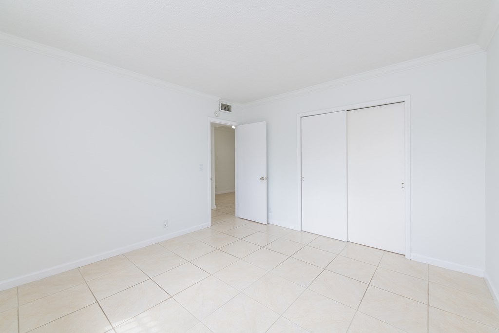 an empty room with white walls and tiled flooring