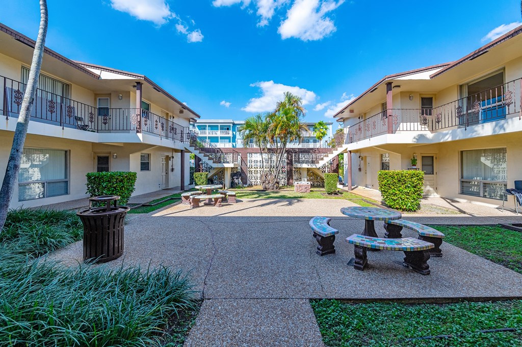 a courtyard with a table and benches in front of some apartments