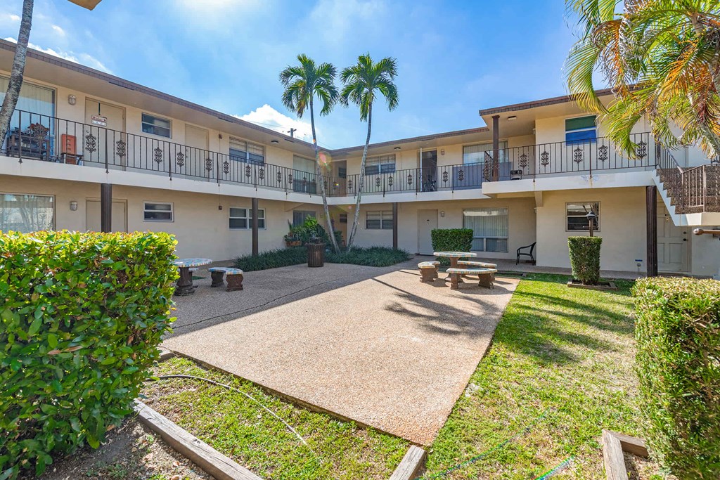 a courtyard with picnic tables and palm trees