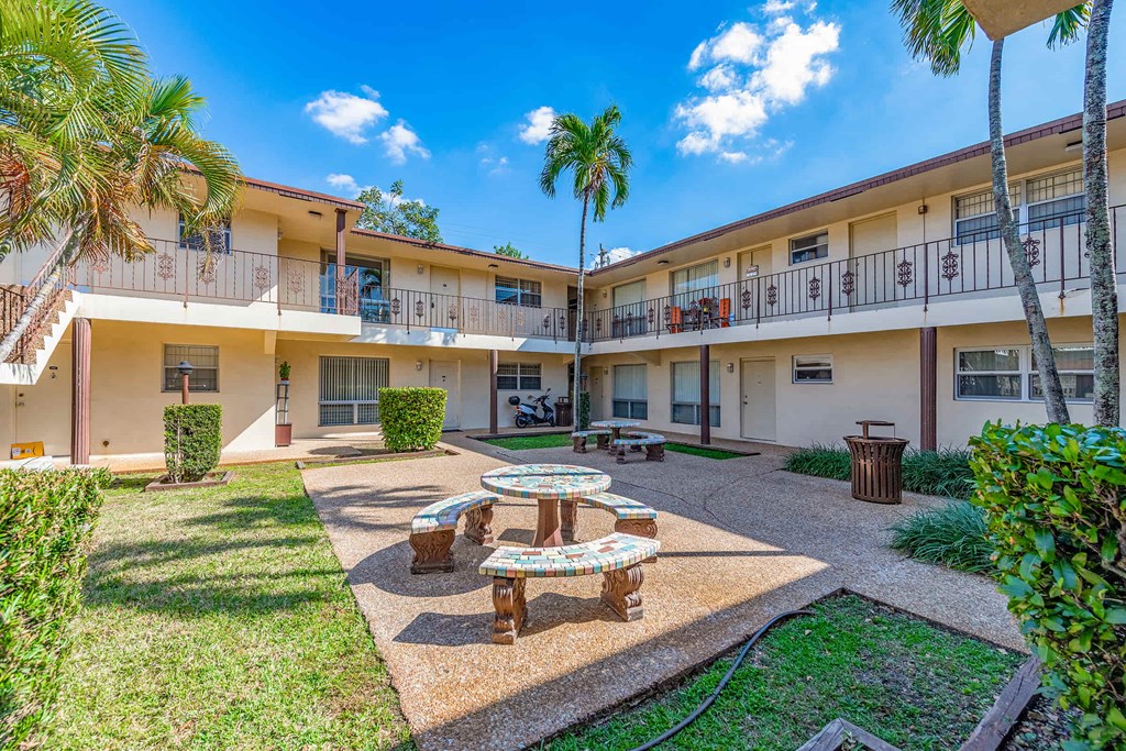 a courtyard with a table and benches in front of a building