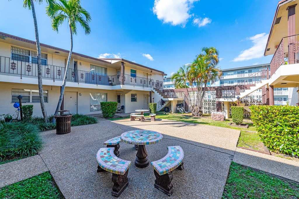 a courtyard with tables and benches in front of a building