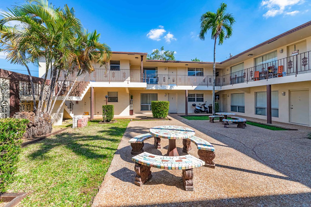 a courtyard with a table and benches in front of a building