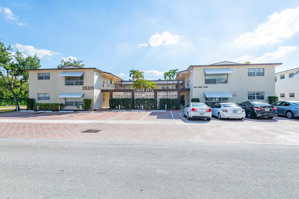 a parking lot in front of an apartment building with cars parked