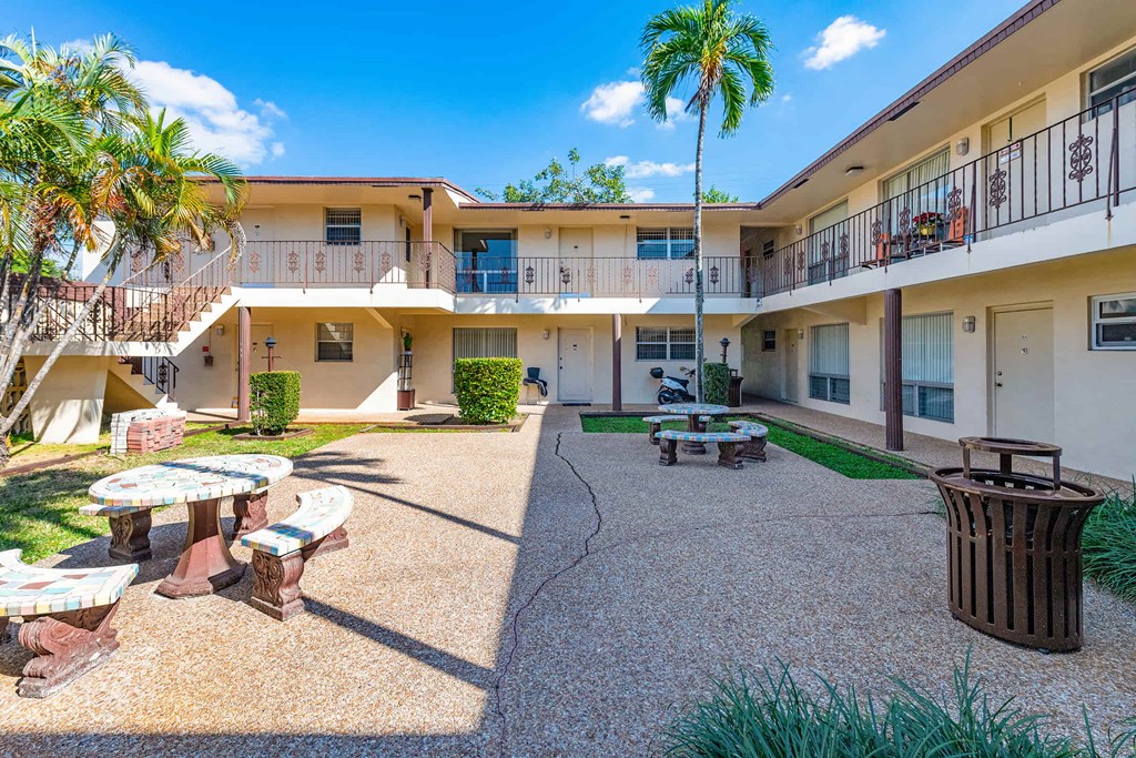 a courtyard with tables and benches in the courtyard of a building