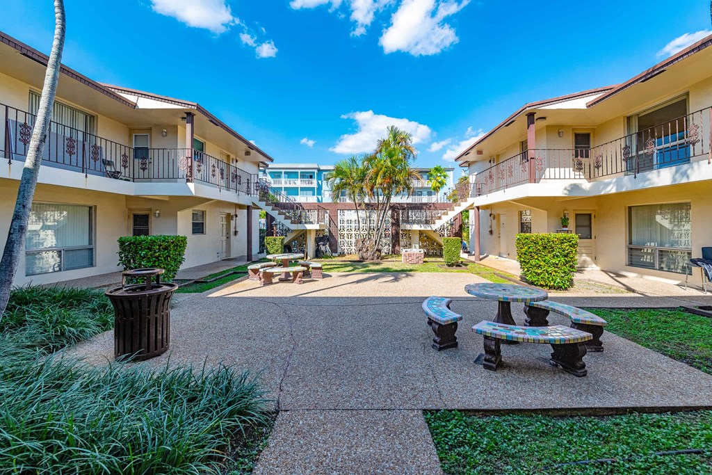 a courtyard with a table and benches in front of some apartments