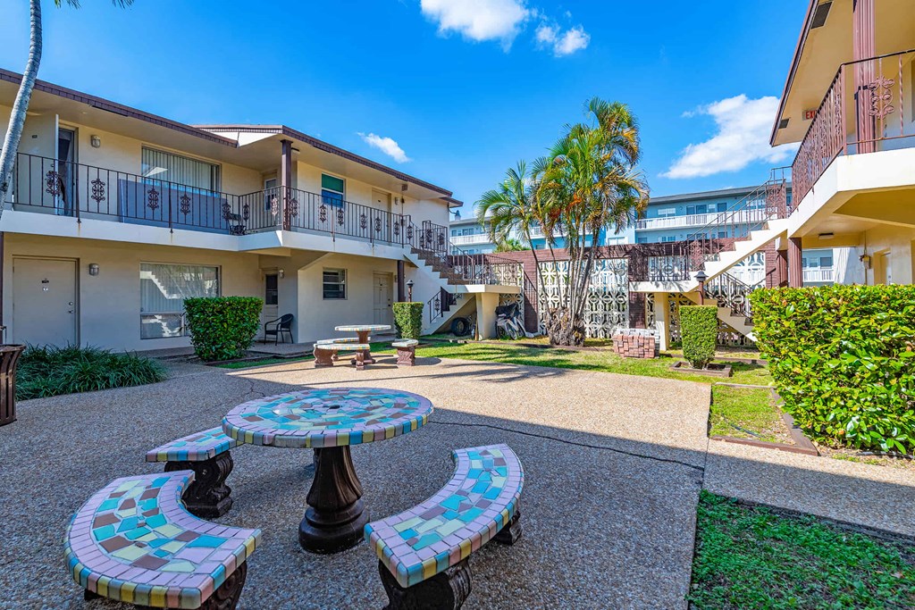 a courtyard with tables and benches in front of some apartments